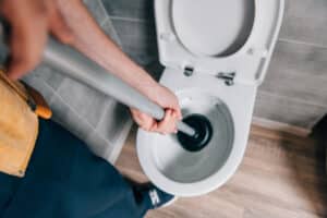 plumber uses plunger in toilet
